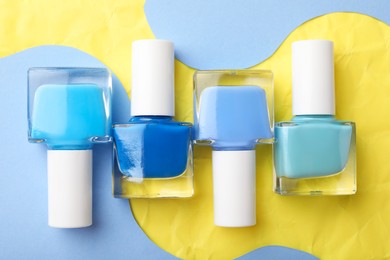 Photo of Set of nail polishes in bottles on color background, flat lay