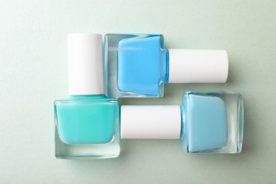 Photo of Set of different nail polishes in bottles on turquoise background, flat lay