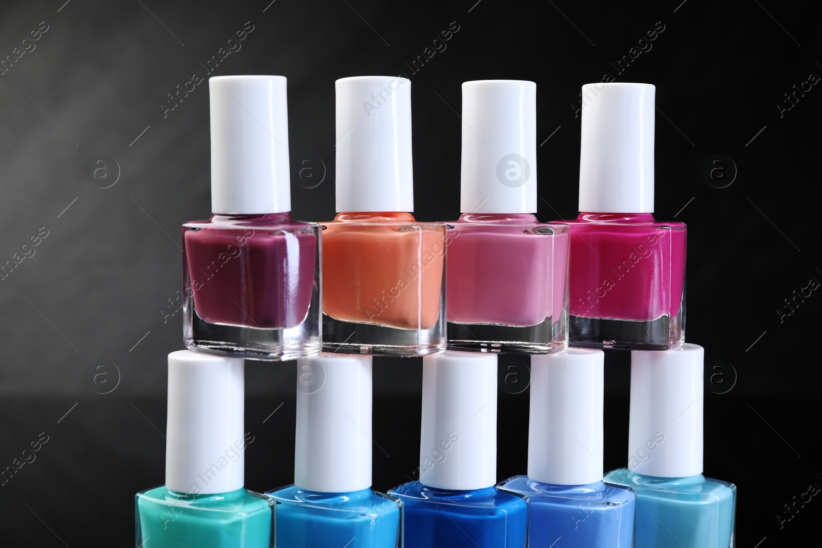 Photo of Set of different nail polishes in bottles on dark background, closeup