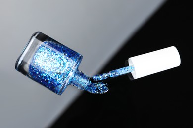 Photo of Open nail polish in bottle and brush on mirror surface, top view