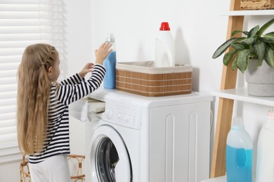 Photo of Little helper. Cute girl doing laundry at home