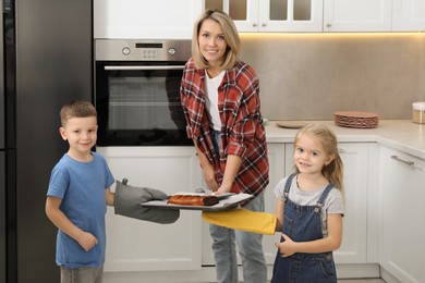 Photo of Little helpers. Children baking with their mother at home