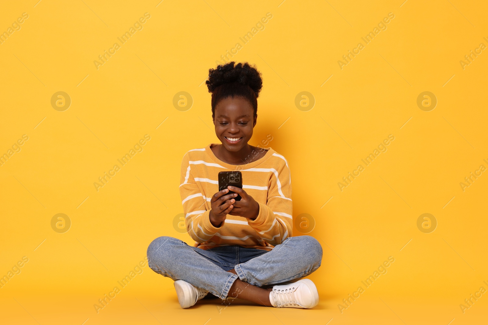 Photo of Happy woman with smartphone on yellow background