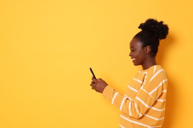 Photo of Happy woman with smartphone on yellow background. Space for text