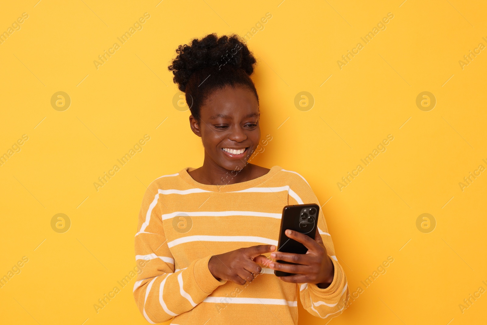 Photo of Happy woman with smartphone on yellow background