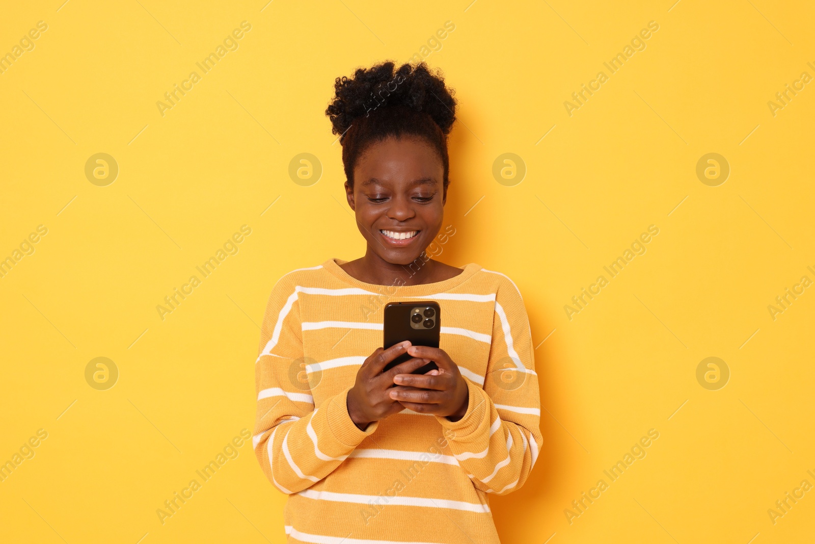 Photo of Happy woman with smartphone on yellow background