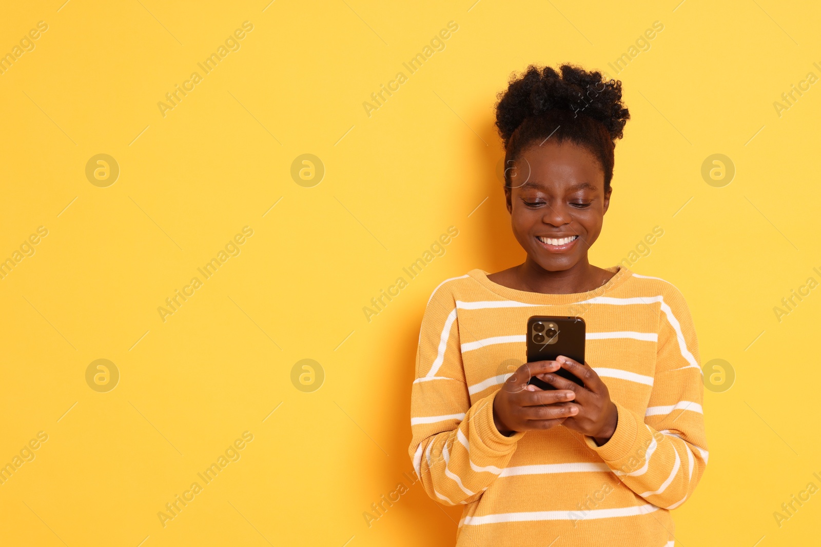 Photo of Happy woman with smartphone on yellow background. Space for text