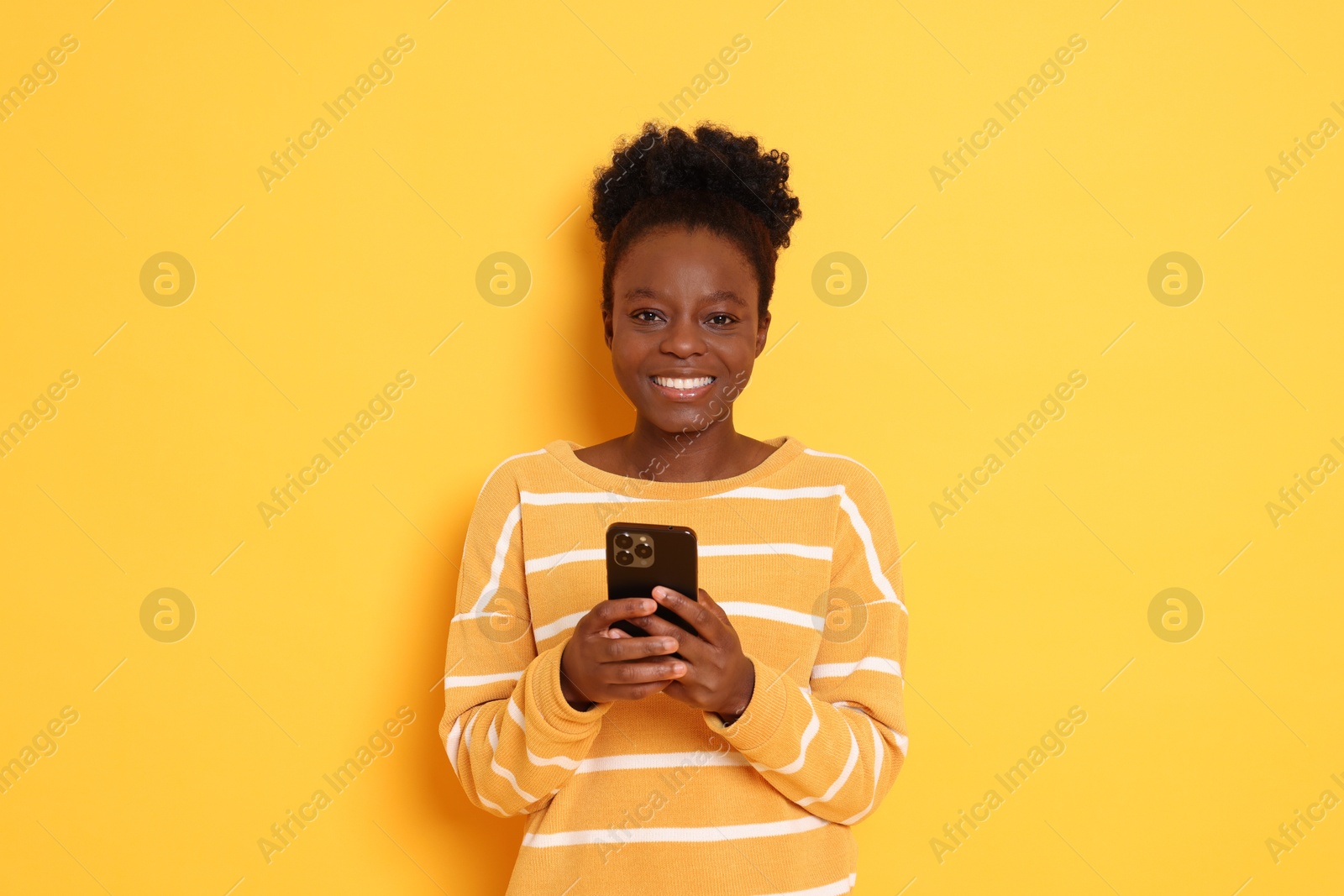 Photo of Happy woman with smartphone on yellow background