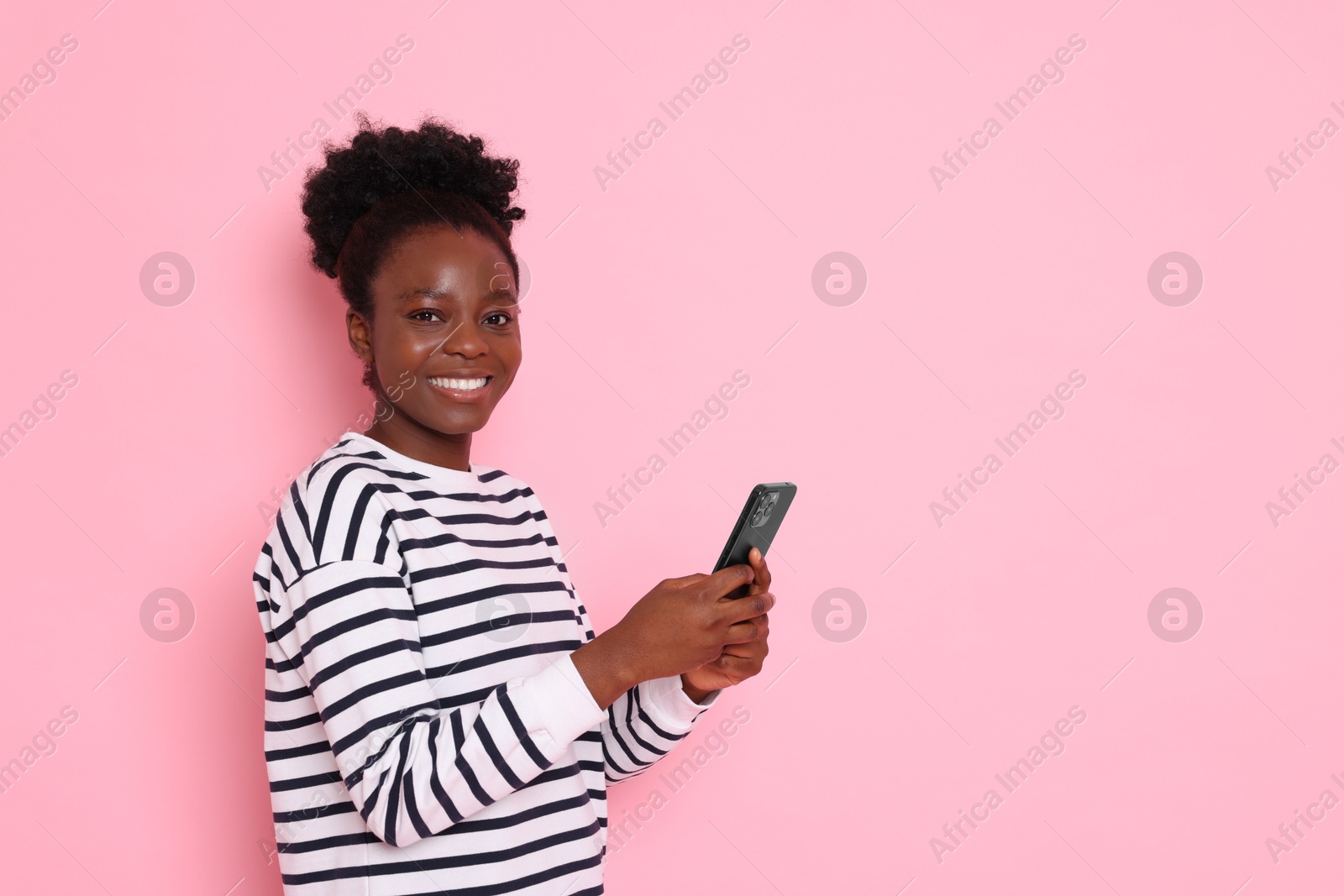 Photo of Happy woman with smartphone on pink background. Space for text