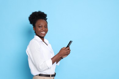 Photo of Happy woman with smartphone on light blue background. Space for text