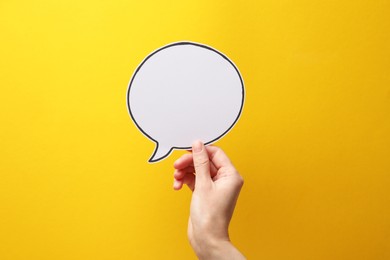 Photo of Woman holding blank speech bubble on yellow background, closeup. Space for text