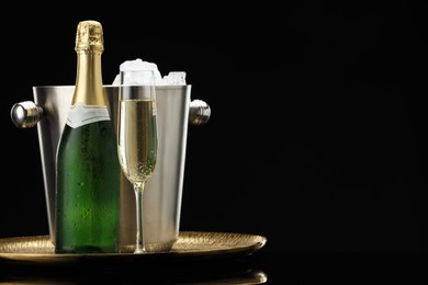 Photo of Sparkling wine and cooler bucket on black background. Space for text