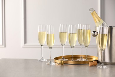 Photo of Bottle of sparkling wine in cooler bucket and glasses on grey table