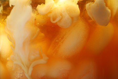 Photo of Refreshing coffee with ice and milk as background, closeup