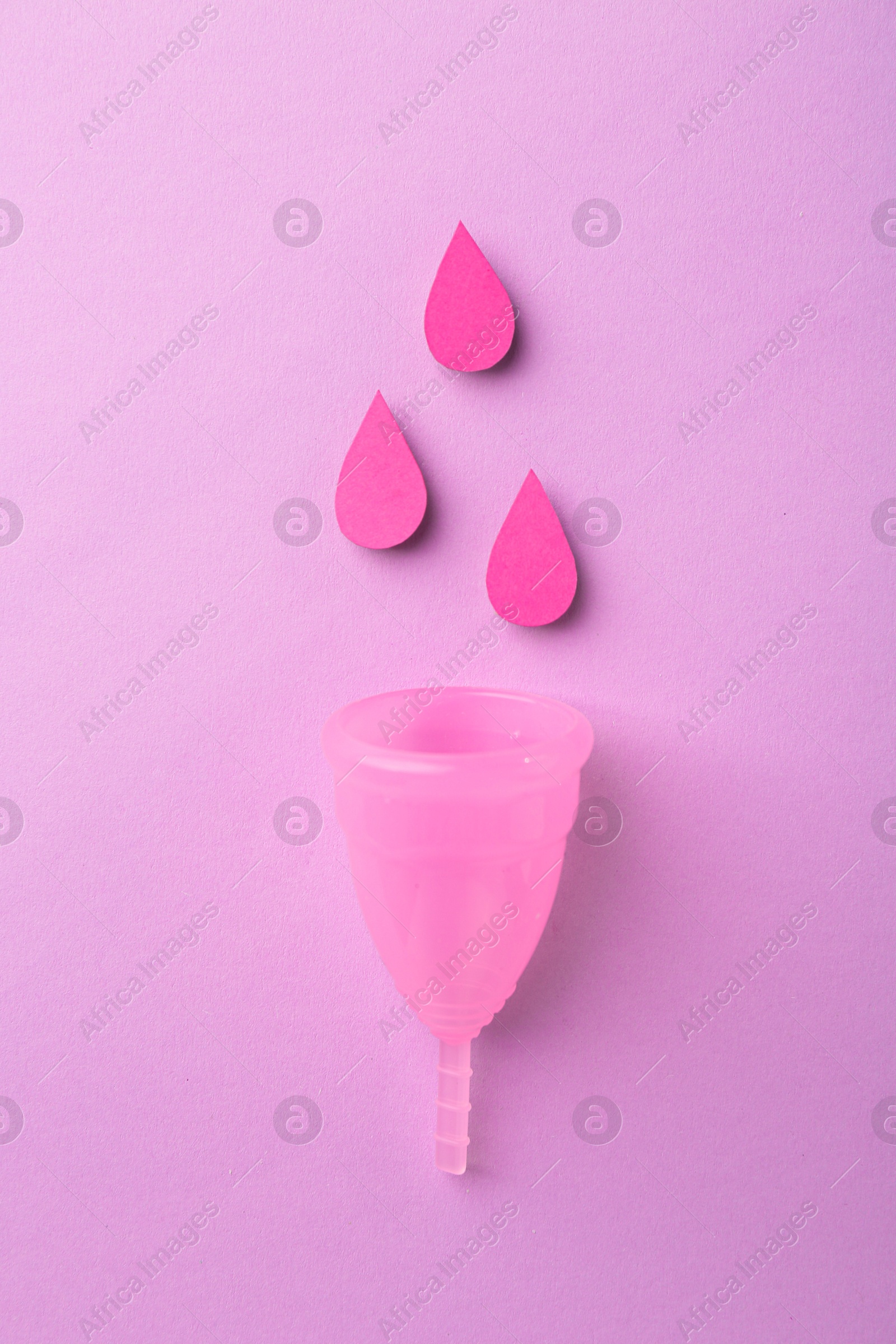 Photo of Menstrual cup and paper cutouts of drops on violet background, flat lay