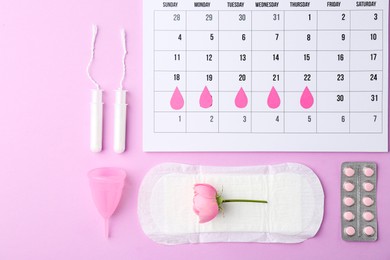 Photo of Flat lay composition with calendar and menstrual products on violet background