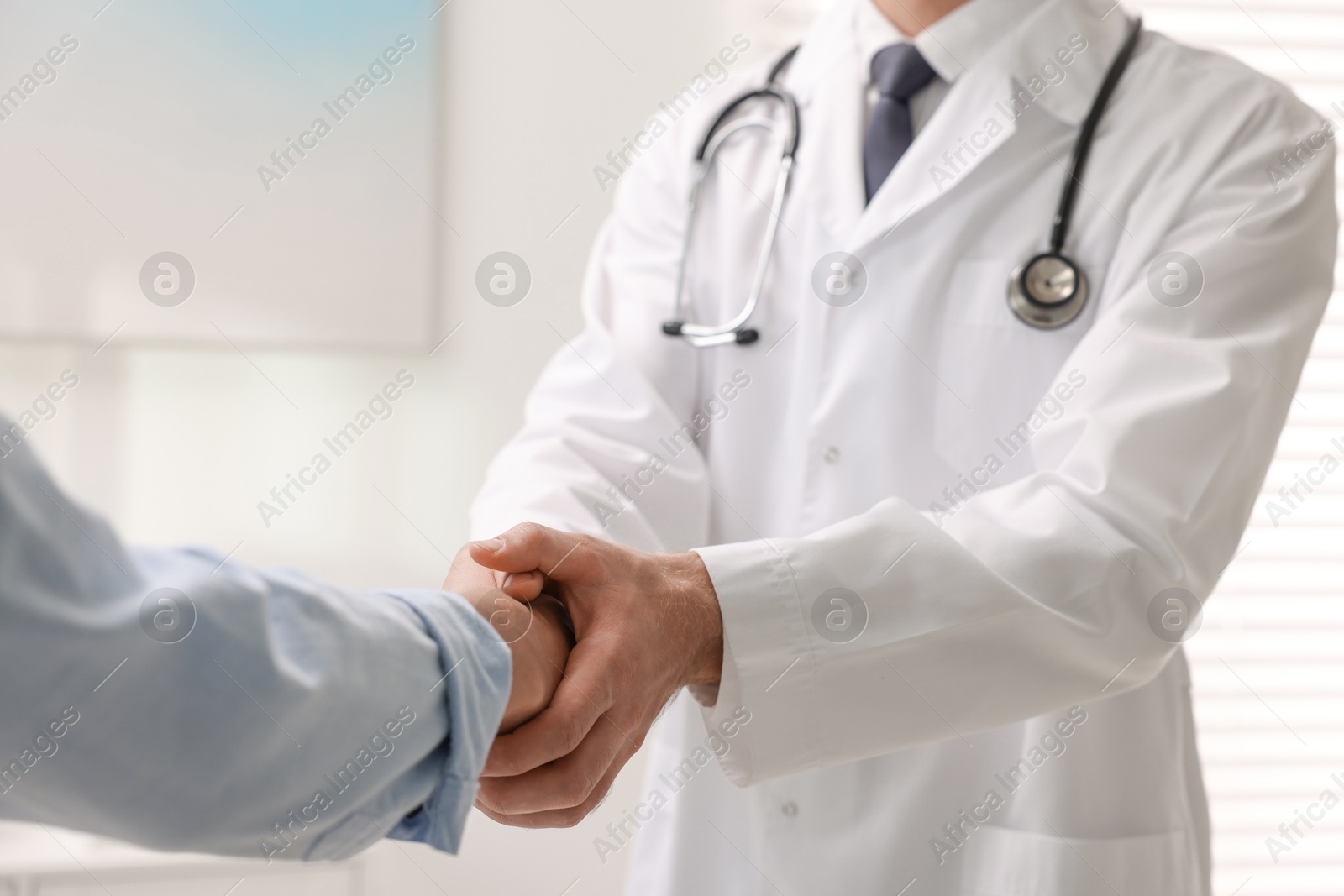 Photo of Doctor shaking hands with patient in hospital, closeup