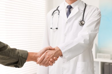 Photo of Doctor shaking hands with patient in hospital, closeup