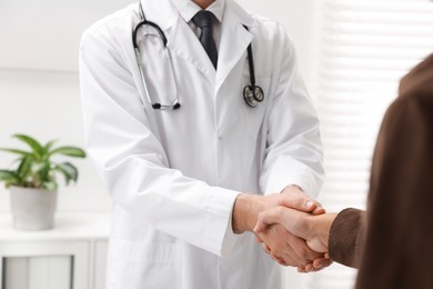 Photo of Doctor shaking hands with patient in hospital, closeup