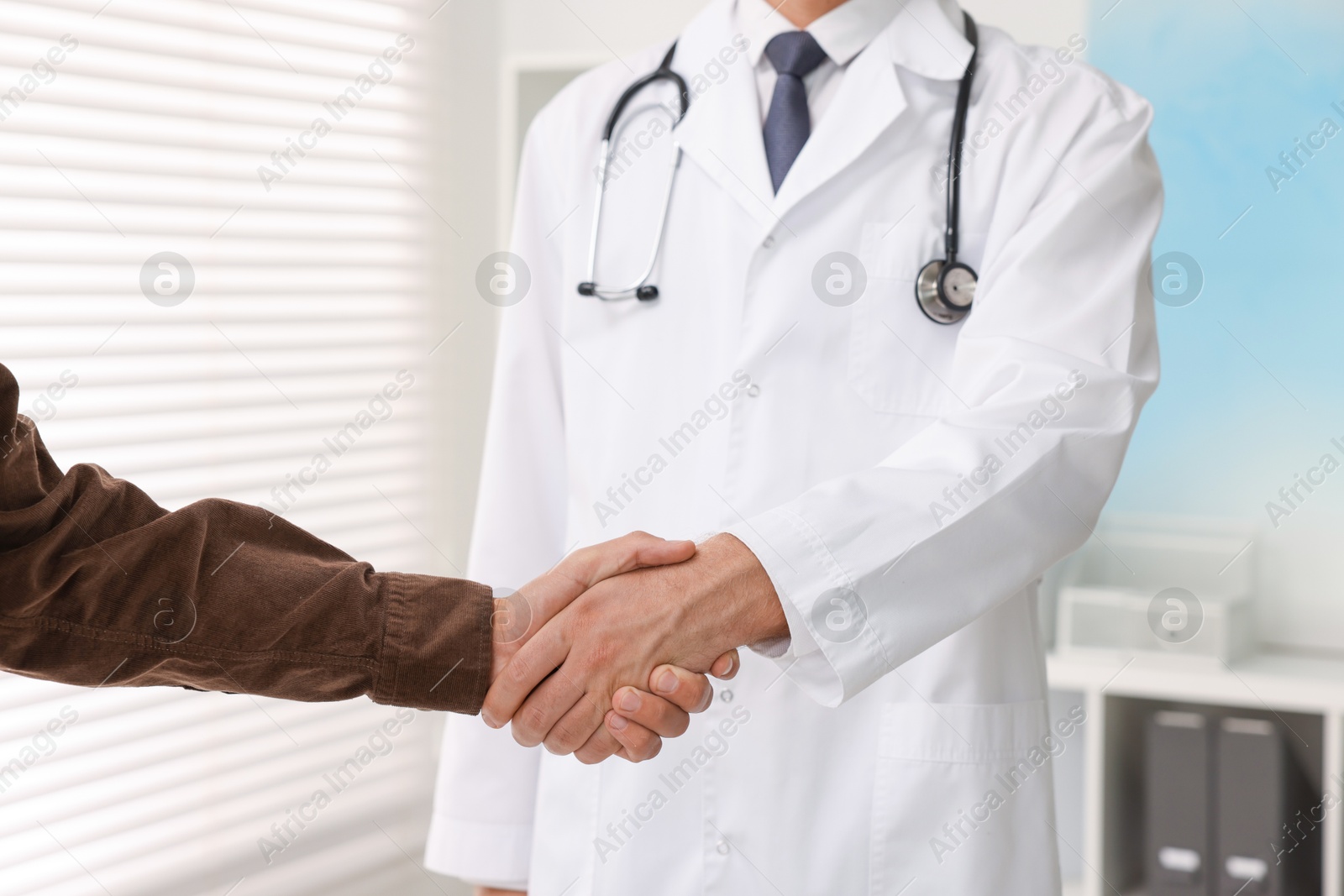 Photo of Doctor shaking hands with patient in hospital, closeup