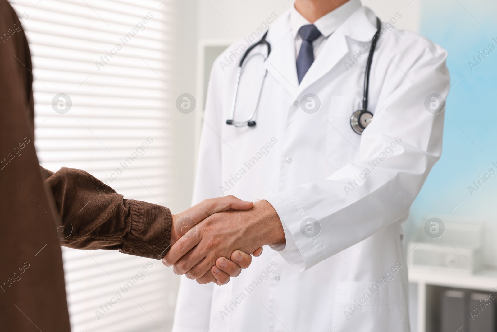 Photo of Doctor shaking hands with patient in hospital, closeup