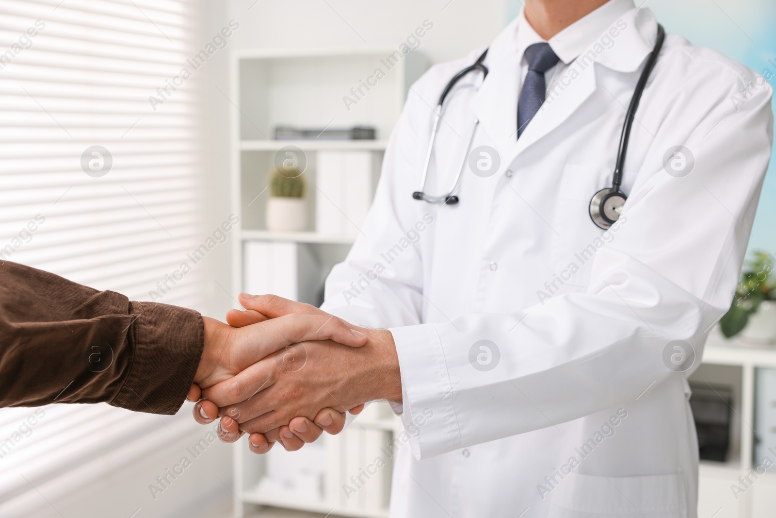 Photo of Doctor shaking hands with patient in hospital, closeup