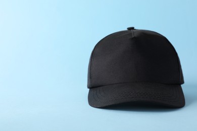 Photo of Stylish black baseball cap on light blue background. Mockup for design