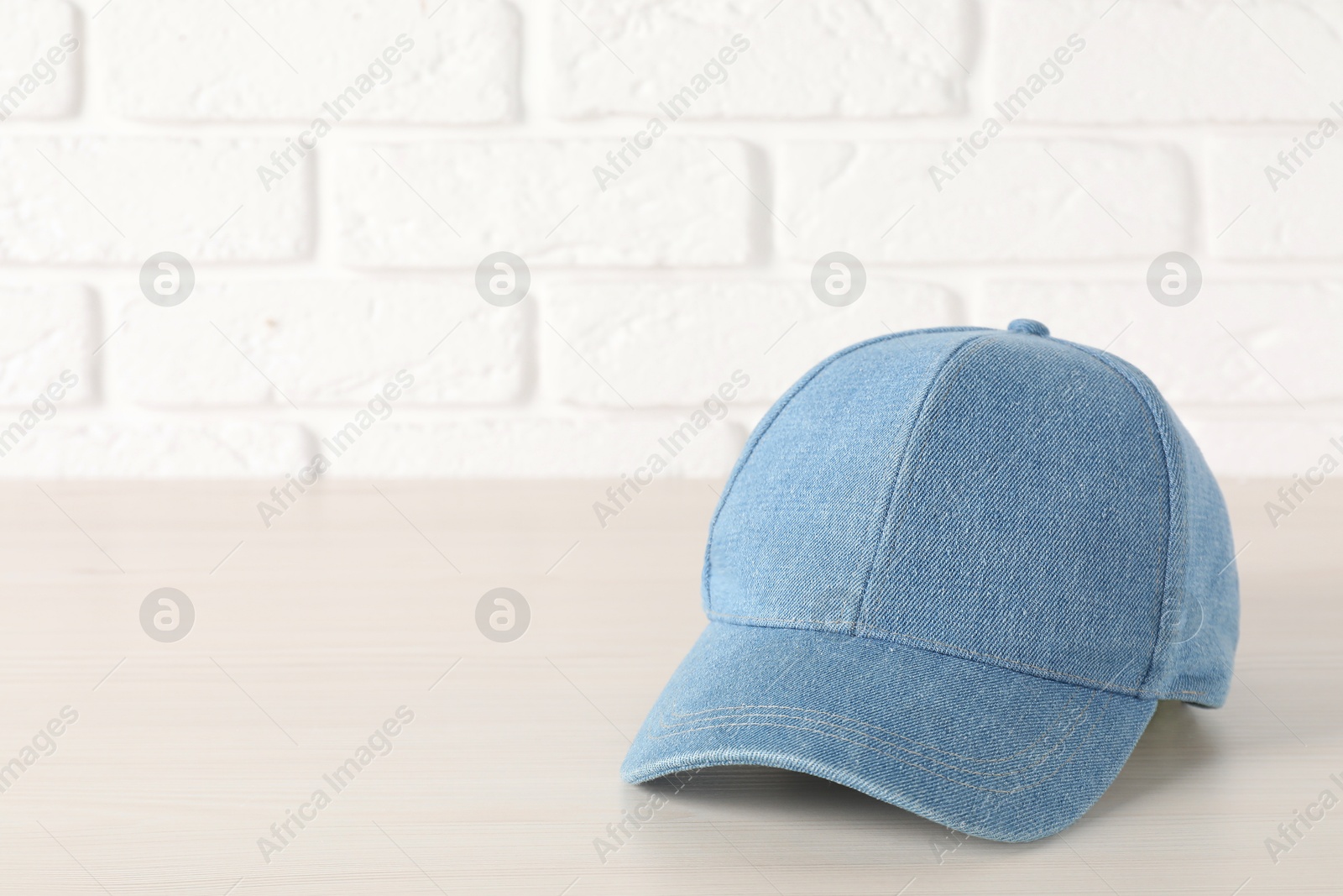 Photo of Stylish denim baseball cap on wooden table. Mockup for design