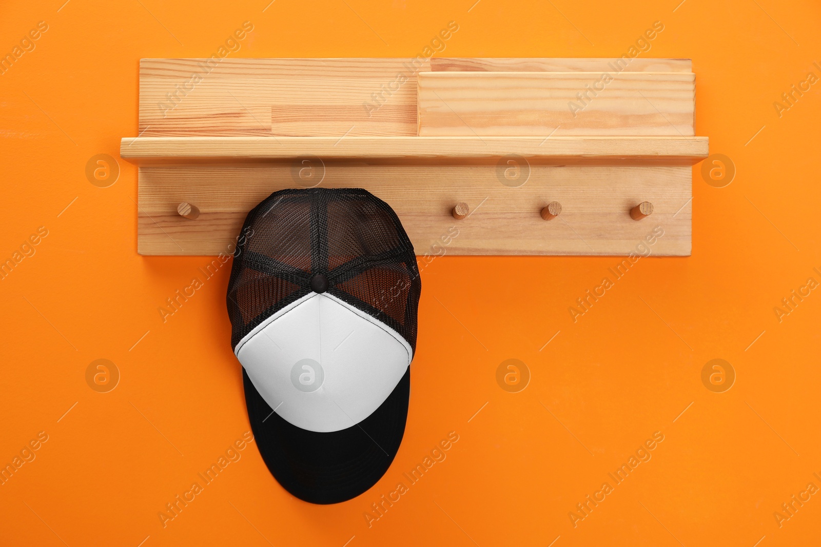 Photo of Stylish baseball cap on orange wall. Mockup for design