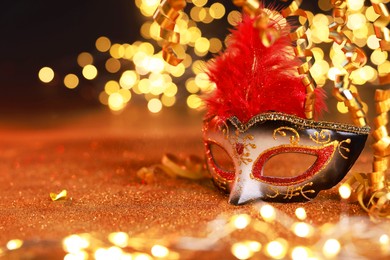 Photo of Beautiful carnival mask on shiny color background, bokeh effect. Space for text