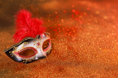 Photo of Beautiful carnival mask on shiny color background, closeup. Space for text