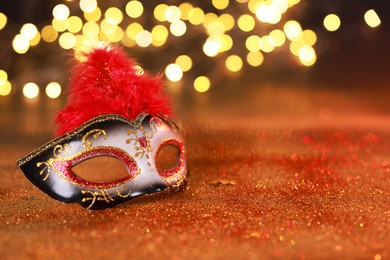 Photo of Beautiful carnival mask on shiny color background, bokeh effect. Space for text