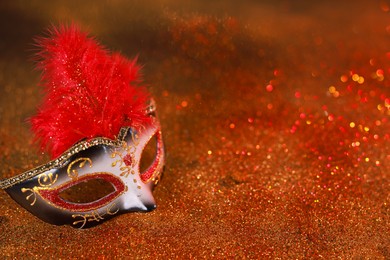 Photo of Beautiful carnival mask on shiny color background, closeup. Space for text