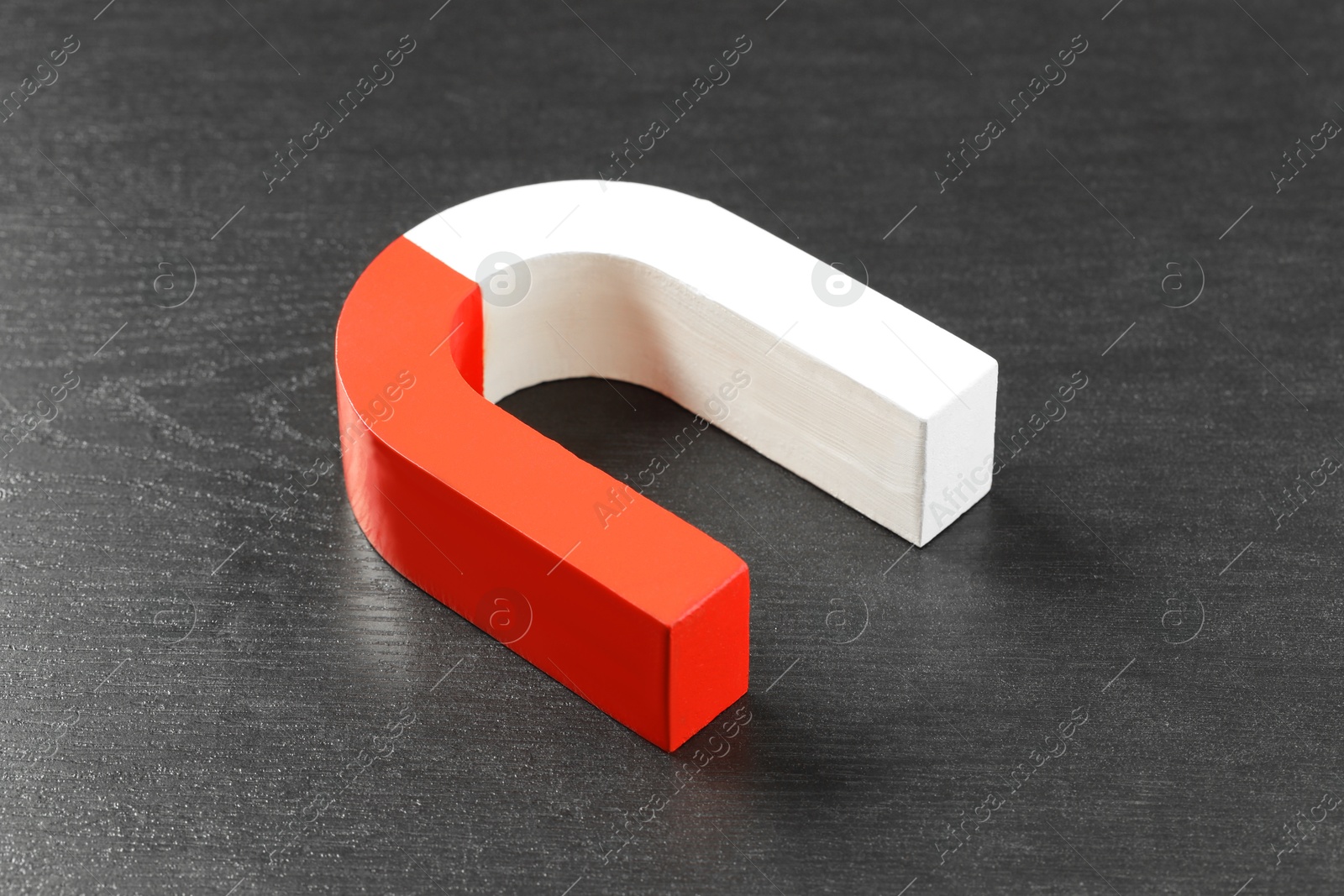 Photo of One horseshoe magnet on black wooden table, closeup