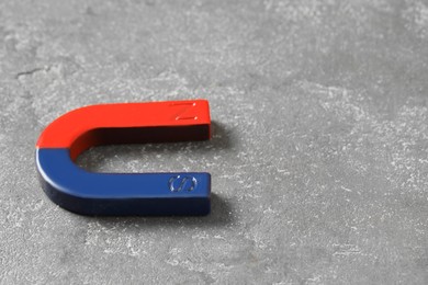 Photo of One horseshoe magnet on grey textured table, closeup. Space for text