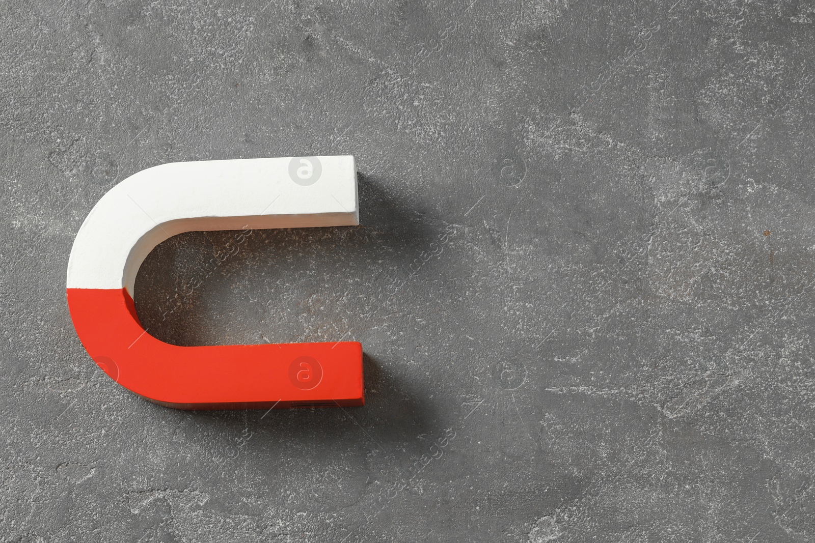 Photo of One horseshoe magnet on grey textured background, top view. Space for text