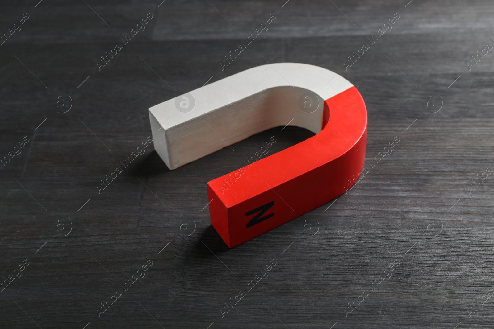 Photo of One horseshoe magnet on black wooden table, closeup