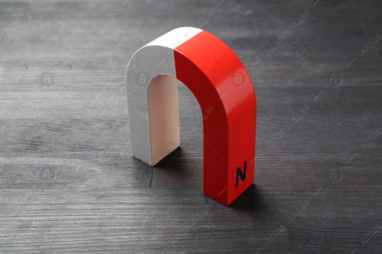 Photo of One horseshoe magnet on black wooden table