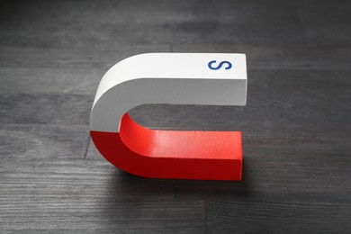 Photo of One horseshoe magnet on black wooden table, closeup