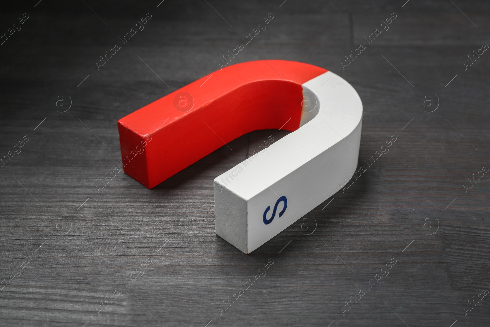 Photo of One horseshoe magnet on black wooden table, closeup