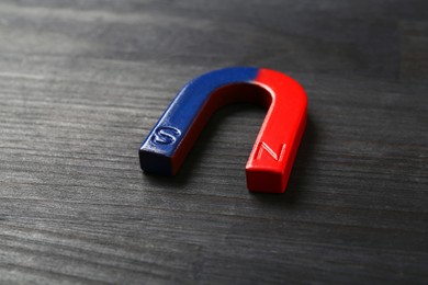 Photo of One horseshoe magnet on black wooden table, closeup