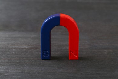 Photo of One horseshoe magnet on black wooden table, closeup