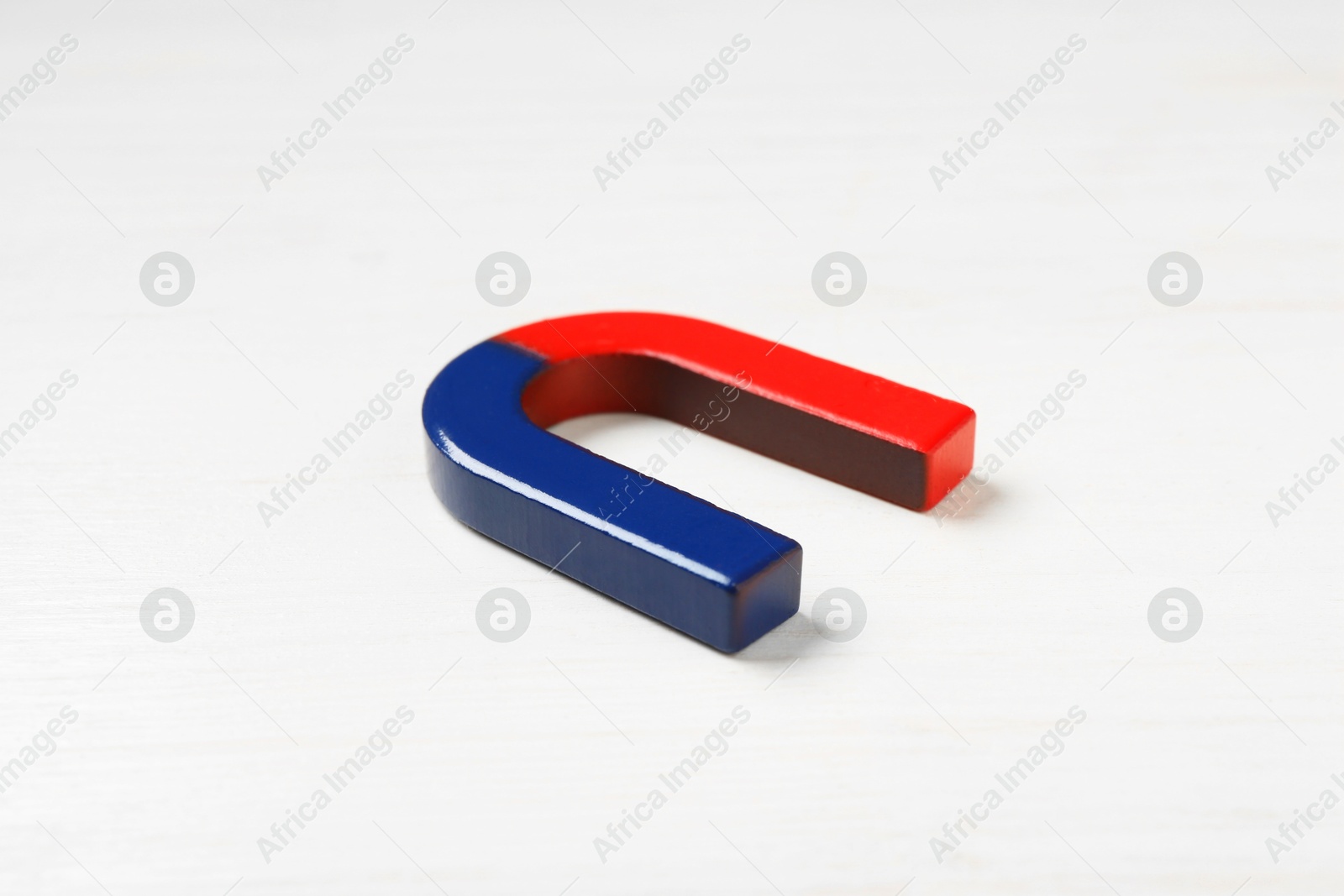 Photo of One horseshoe magnet on white wooden table, closeup