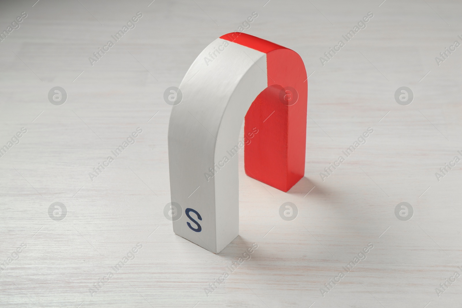 Photo of One horseshoe magnet on white wooden table