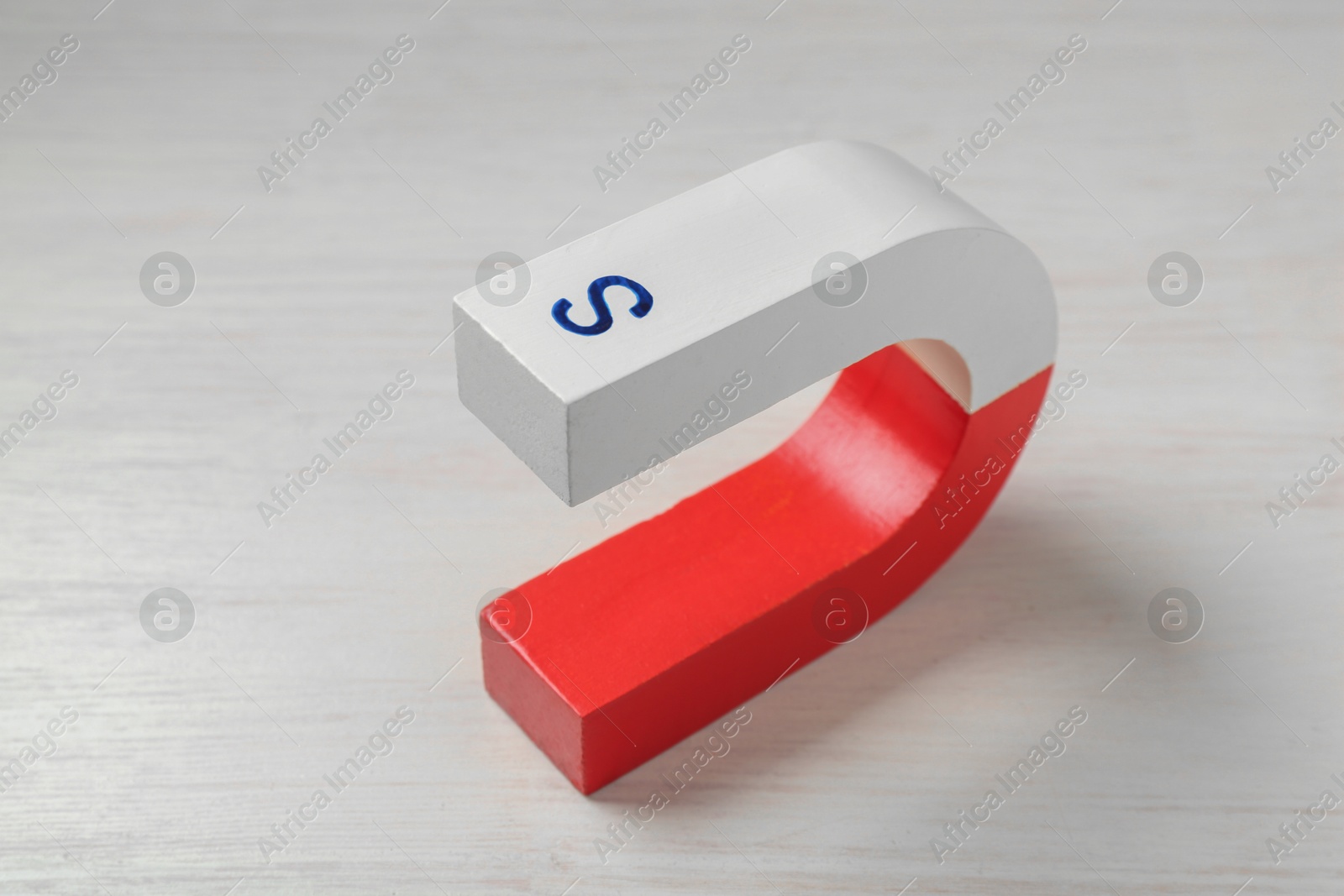 Photo of One horseshoe magnet on white wooden table, closeup