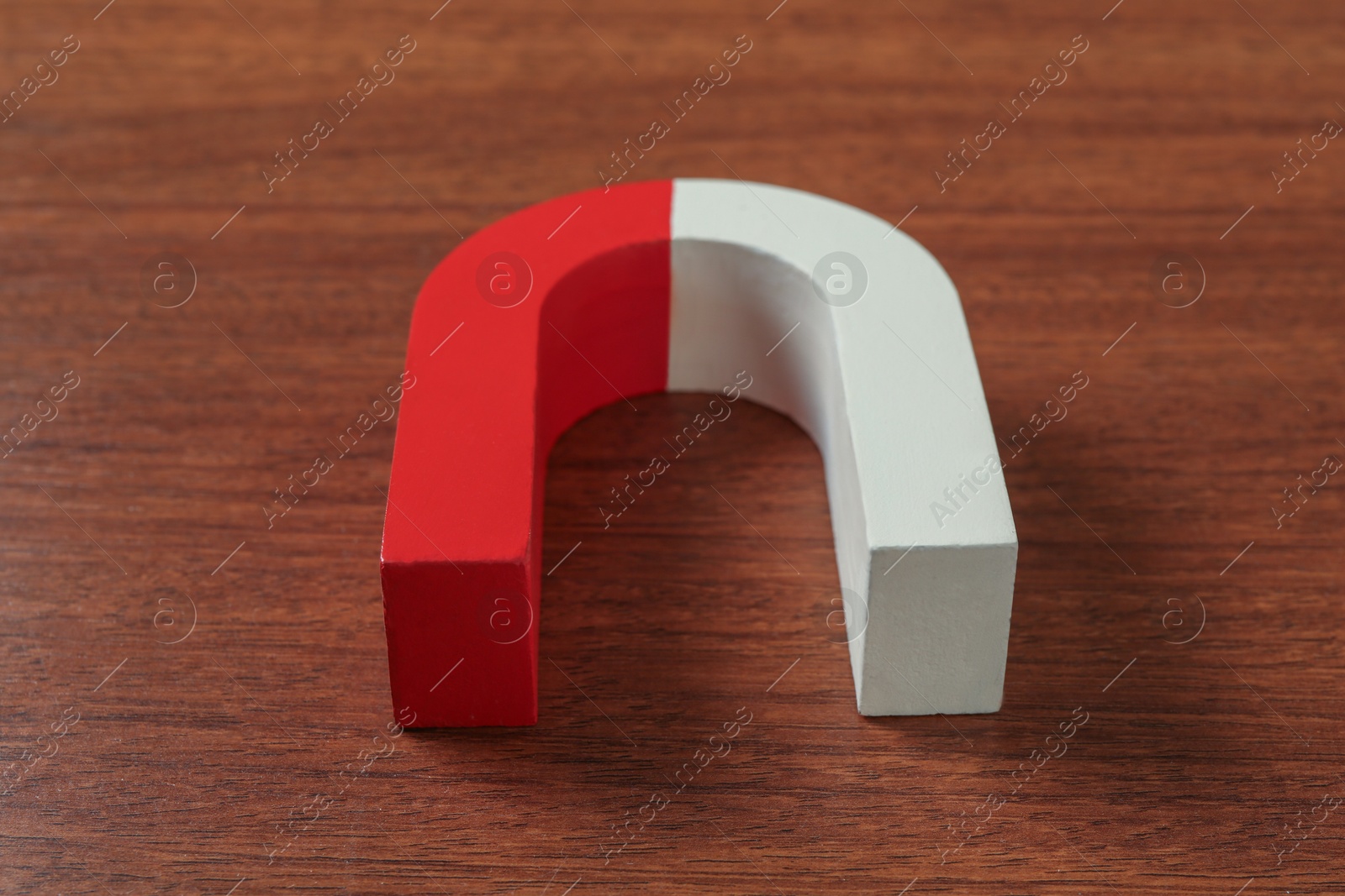 Photo of One horseshoe magnet on wooden table, closeup