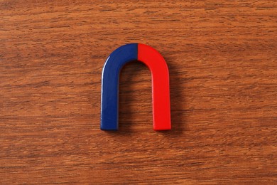 Photo of One horseshoe magnet on wooden background, top view