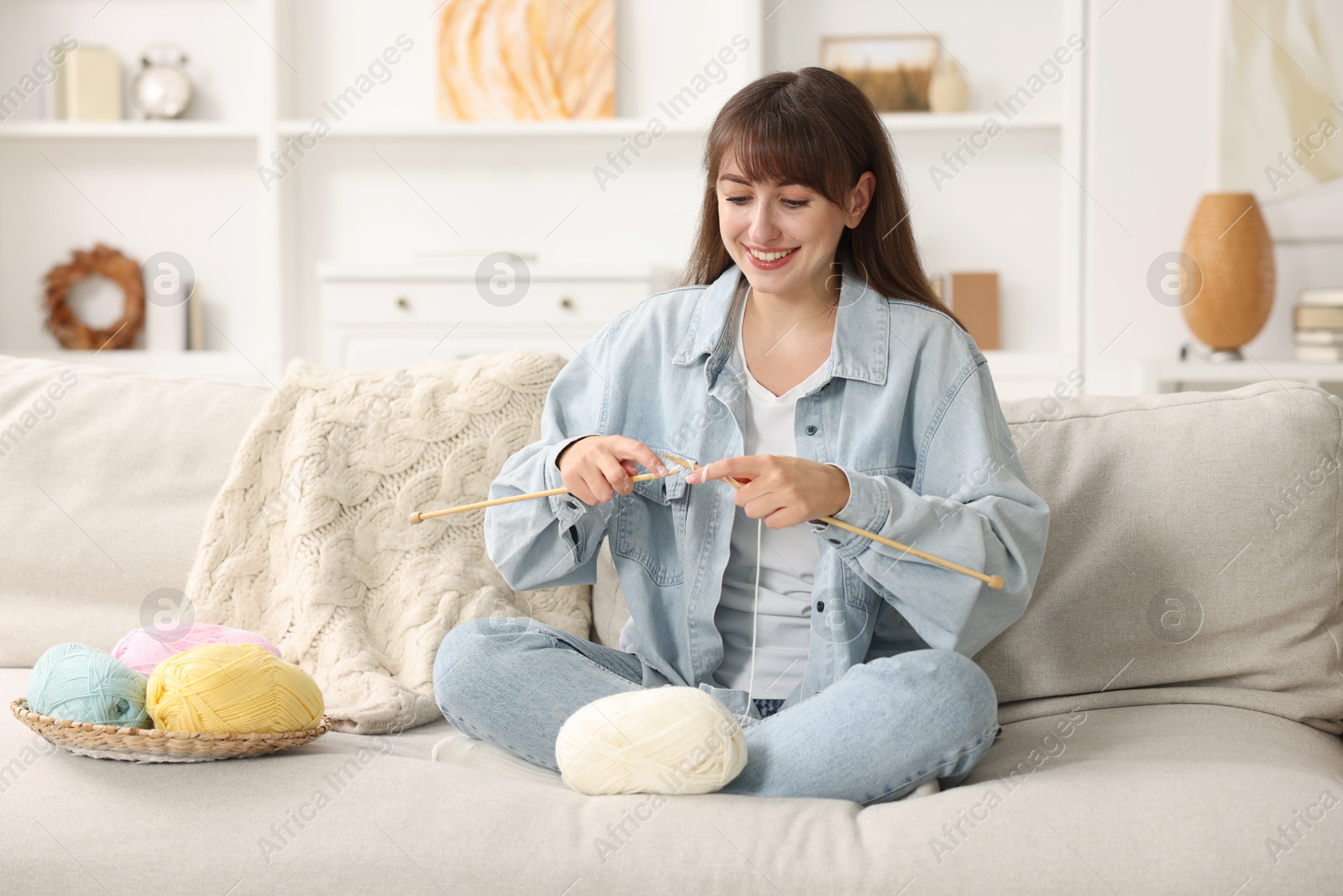 Photo of Beautiful woman knitting on sofa at home