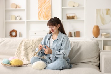 Photo of Beautiful woman knitting on sofa at home