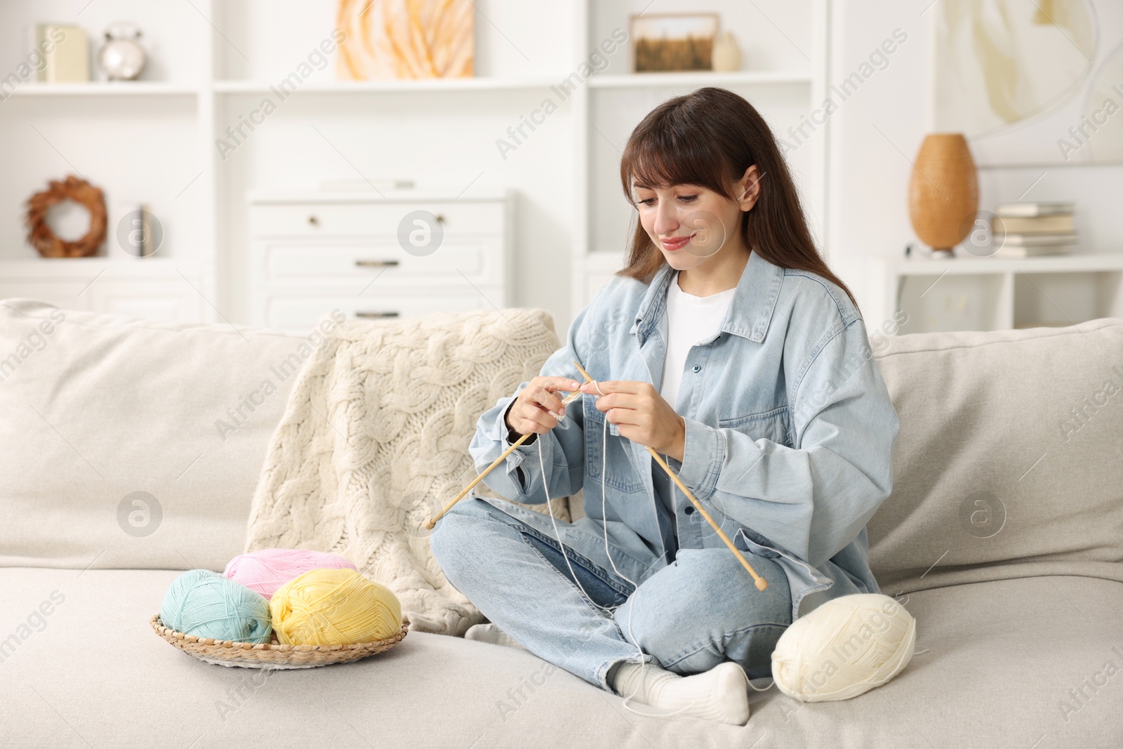 Photo of Beautiful woman knitting on sofa at home